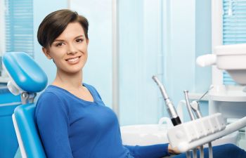 Smiling Woman in a Dental Chair After Cosmetic Dentistry Treatment