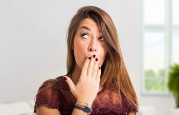 woman covering her mouth with her hand due to bad breath
