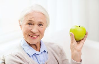 Happy Senior Woman with a Green Apple in Hand